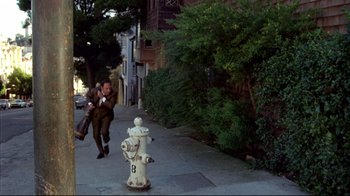 Movie still from “What's Up, Doc?” (1972), directed by Peter Bogdanovich – A fire hydrant on the side of the street with a man running next to it; Wide shot, High angle