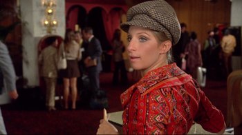 Movie still from “What's Up, Doc?” (1972), directed by Peter Bogdanovich – A woman wearing a hat and holding a pen; Medium shot, Over the shoulder angle