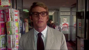 Movie still from “What's Up, Doc?” (1972), directed by Peter Bogdanovich – A man in a suit and tie standing in a room; Close Up shot, Over the shoulder angle