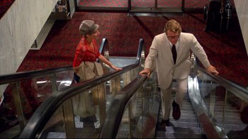 Movie still from “What's Up, Doc?” (1972), directed by Peter Bogdanovich – A man and a woman on an escalator; Wide shot, Low angle