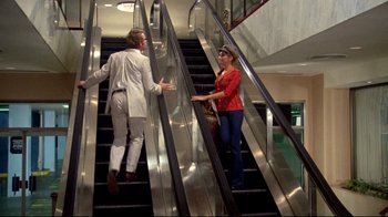 Movie still from “What's Up, Doc?” (1972), directed by Peter Bogdanovich – A man and a woman on an escalator talking to each other; Wide shot, Low angle
