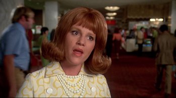 Movie still from “What's Up, Doc?” (1972), directed by Peter Bogdanovich – A woman in a yellow and white dress with a pearl necklace; Close Up shot, Low angle