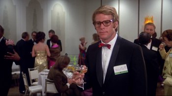 Movie still from “What's Up, Doc?” (1972), directed by Peter Bogdanovich – A man holding a glass of wine in a suit; Medium shot, Low angle