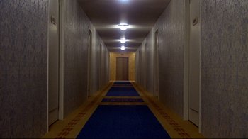 Movie still from “What's Up, Doc?” (1972), directed by Peter Bogdanovich – A long hallway with a blue carpet and a blue door; Extreme Wide shot, High angle