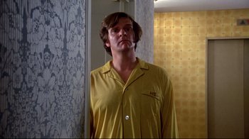 Movie still from “What's Up, Doc?” (1972), directed by Peter Bogdanovich – A man in a yellow shirt is standing in front of a mirror; Medium shot, Low angle