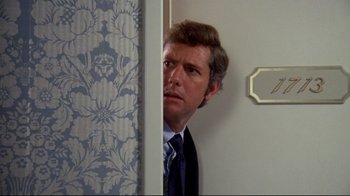 Movie still from “What's Up, Doc?” (1972), directed by Peter Bogdanovich – A person wearing a suit near a wall; Close Up shot, Over the shoulder angle