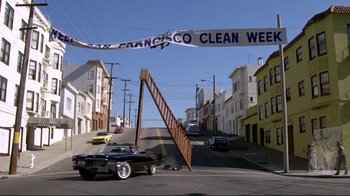 Movie still from “What's Up, Doc?” (1972), directed by Peter Bogdanovich – A car driving down a street next to some buildings; Wide shot, Low angle