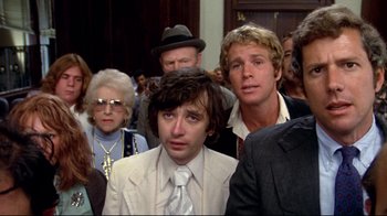Movie still from “What's Up, Doc?” (1972), directed by Peter Bogdanovich – A group of people standing around each other in front of a building; Close Up shot, High angle
