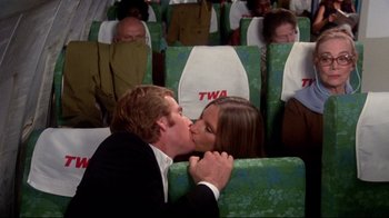 Movie still from “What's Up, Doc?” (1972), directed by Peter Bogdanovich – A man and a woman kissing on a plane; Wide shot, High angle