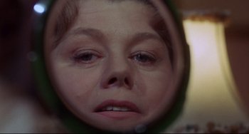 Movie still from “What's the Matter with Helen?” (1971), directed by Curtis Harrington – A woman's reflection in a mirror of her face; Close Up shot, Low angle