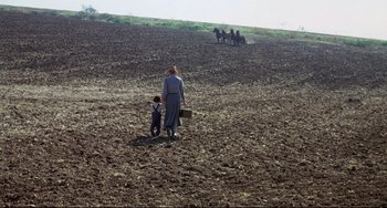Movie still from “What's the Matter with Helen?” (1971), directed by Curtis Harrington – A woman and a child are standing in the middle of a plowed field; Extreme Wide shot, High angle