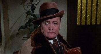 Movie still from “What's the Matter with Helen?” (1971), directed by Curtis Harrington – An older man wearing a brown hat and a brown coat; Close Up shot, Over the shoulder angle