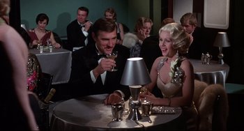 Movie still from “What's the Matter with Helen?” (1971), directed by Curtis Harrington – A man and a woman sitting in front of a lamp; Medium shot, Low angle