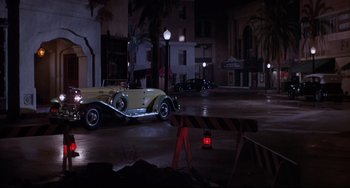 Movie still from “What's the Matter with Helen?” (1971), directed by Curtis Harrington – An antique car is parked in the middle of the street; Wide shot, High angle