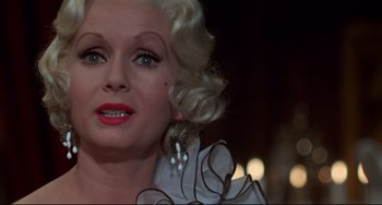 Movie still from “What's the Matter with Helen?” (1971), directed by Curtis Harrington – An older woman with blonde curly hair wearing a white dress; Close Up shot, Low angle