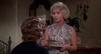 Movie still from “What's the Matter with Helen?” (1971), directed by Curtis Harrington – An older woman is holding a plate and talking to a younger woman; Medium shot, Over the shoulder angle