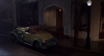 Movie still from “What's the Matter with Helen?” (1971), directed by Curtis Harrington – An old car parked in front of a building; Wide shot, High angle