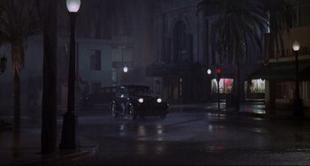 Movie still from “What's the Matter with Helen?” (1971), directed by Curtis Harrington – A car is driving down the street in the rain; Extreme Wide shot, High angle