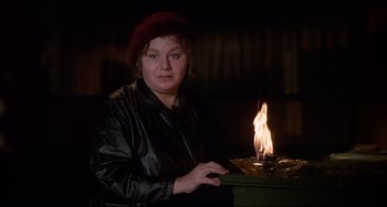Movie still from “What's the Matter with Helen?” (1971), directed by Curtis Harrington – A woman sitting in front of a table with a lit candle; Medium shot, Low angle
