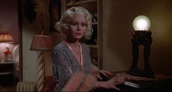 Movie still from “What's the Matter with Helen?” (1971), directed by Curtis Harrington – A woman with blonde curly hair sitting at a table; Close Up shot, High angle
