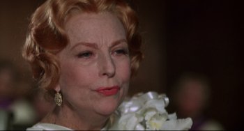 Movie still from “What's the Matter with Helen?” (1971), directed by Curtis Harrington – An older woman with red hair and a white flower bouquet; Close Up shot, Over the shoulder angle