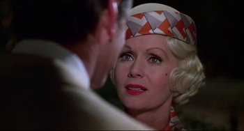 Movie still from “What's the Matter with Helen?” (1971), directed by Curtis Harrington – An older woman wearing an orange and white hat; Close Up shot, Over the shoulder angle