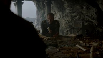 Movie still from “Game of Thrones” (2011), created by D.B. Weiss – A man sitting at a table in front of a stone wall; Medium shot, Low angle