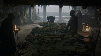 Movie still from “Game of Thrones” (2011), created by D.B. Weiss – A man standing next to a bear in a cave; Wide shot, Low angle