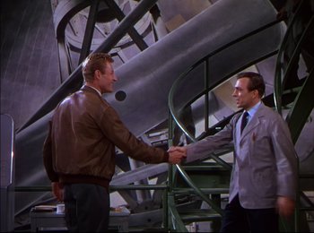 Movie still from “When Worlds Collide” (1951), directed by Rudolph Maté – Two men shaking hands in front of a metal structure; Medium shot, High angle