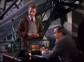 Movie still from “When Worlds Collide” (1951), directed by Rudolph Maté – Two men are sitting at a table and one of them is talking; Medium shot, Over the shoulder angle