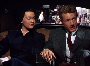 Movie still from “When Worlds Collide” (1951), directed by Rudolph Maté – A man and a woman sitting next to each other in the back of a car; Medium shot, Low angle