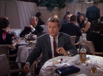 Movie still from “When Worlds Collide” (1951), directed by Rudolph Maté – A man sitting at a table in front of a bunch of people; Medium shot, Over the shoulder angle