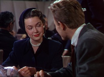 Movie still from “When Worlds Collide” (1951), directed by Rudolph Maté – A woman sitting at a table with a man in a suit; Medium shot, Over the shoulder angle