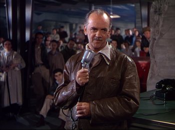Movie still from “When Worlds Collide” (1951), directed by Rudolph Maté – An older man holding a microphone in front of a crowd; Medium shot, Over the shoulder angle