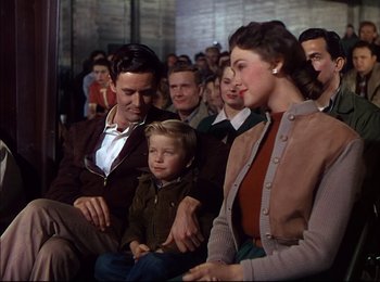 Movie still from “When Worlds Collide” (1951), directed by Rudolph Maté – A man and a woman sitting next to each other with a child; Medium shot, Over the shoulder angle