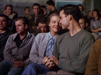 Movie still from “When Worlds Collide” (1951), directed by Rudolph Maté – A man and a woman sitting next to each other in front of a group of people; Medium shot, High angle