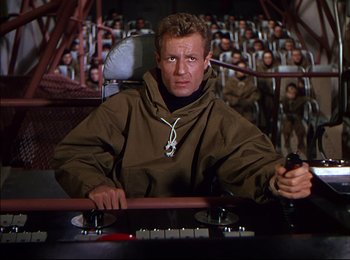 Movie still from “When Worlds Collide” (1951), directed by Rudolph Maté – A man sitting at a table in front of an audience; Medium shot, High angle