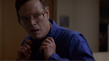 Movie still from “When a Man Falls” (2007), directed by Ryan Eslinger – A man wearing glasses and a blue shirt is fixing his tie; Close Up shot, Over the shoulder angle