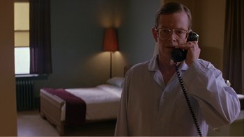 Movie still from “When a Man Falls” (2007), directed by Ryan Eslinger – A man talking on a phone in a room; Medium shot, Low angle