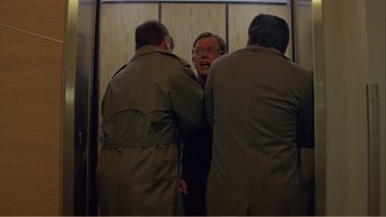 Movie still from “When a Man Falls” (2007), directed by Ryan Eslinger – A man in a suit is looking in the mirror; Medium shot, Low angle