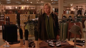 Movie still from “When a Man Falls” (2007), directed by Ryan Eslinger – A woman looking at a pair of shoes in a store; Medium shot, Over the shoulder angle