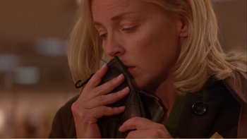 Movie still from “When a Man Falls” (2007), directed by Ryan Eslinger – A woman holding a wallet in front of her face; Close Up shot, Low angle