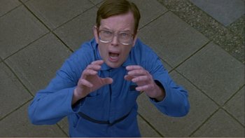 Movie still from “When a Man Falls” (2007), directed by Ryan Eslinger – A man in a blue shirt is holding his hands out; Medium shot, Overhead angle