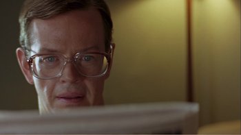Movie still from “When a Man Falls” (2007), directed by Ryan Eslinger – A person wearing glasses looking at a computer screen; Close Up shot, Low angle