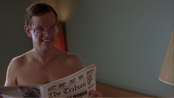 Movie still from “When a Man Falls” (2007), directed by Ryan Eslinger – A shirtless man sitting in front of a woman reading a newspaper; Close Up shot, High angle