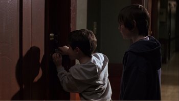 Movie still from “When a Man Falls” (2007), directed by Ryan Eslinger – Two young boys looking at a door knob; Medium shot, Over the shoulder angle