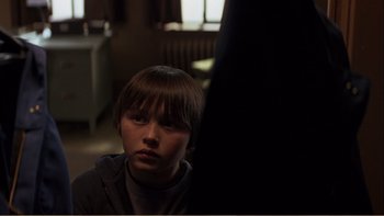 Movie still from “When a Man Falls” (2007), directed by Ryan Eslinger – A young boy sitting in front of a mirror; Close Up shot, Over the shoulder angle