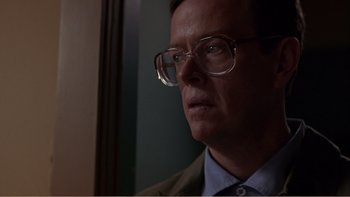 Movie still from “When a Man Falls” (2007), directed by Ryan Eslinger – A person wearing glasses and a suit; Close Up shot, Low angle