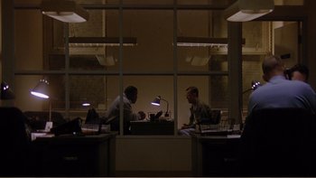 Movie still from “When a Man Falls” (2007), directed by Ryan Eslinger – Two men sitting at a table in a dark room; Extreme Wide shot, High angle