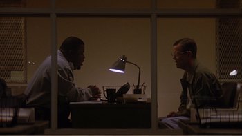 Movie still from “When a Man Falls” (2007), directed by Ryan Eslinger – Two men sitting at a table in front of a laptop; Medium shot, Over the shoulder angle
